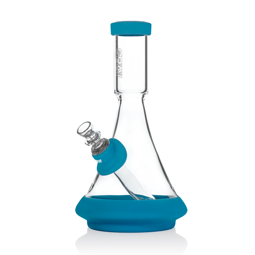A clear glass beaker bong with a blue silicone base and a green mouthpiece.