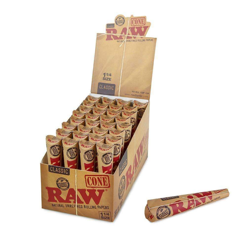 A cardboard box labeled 'RAW Classic 1 1/4 Cones' with several individual rolling papers visible, some with visible branding and text.