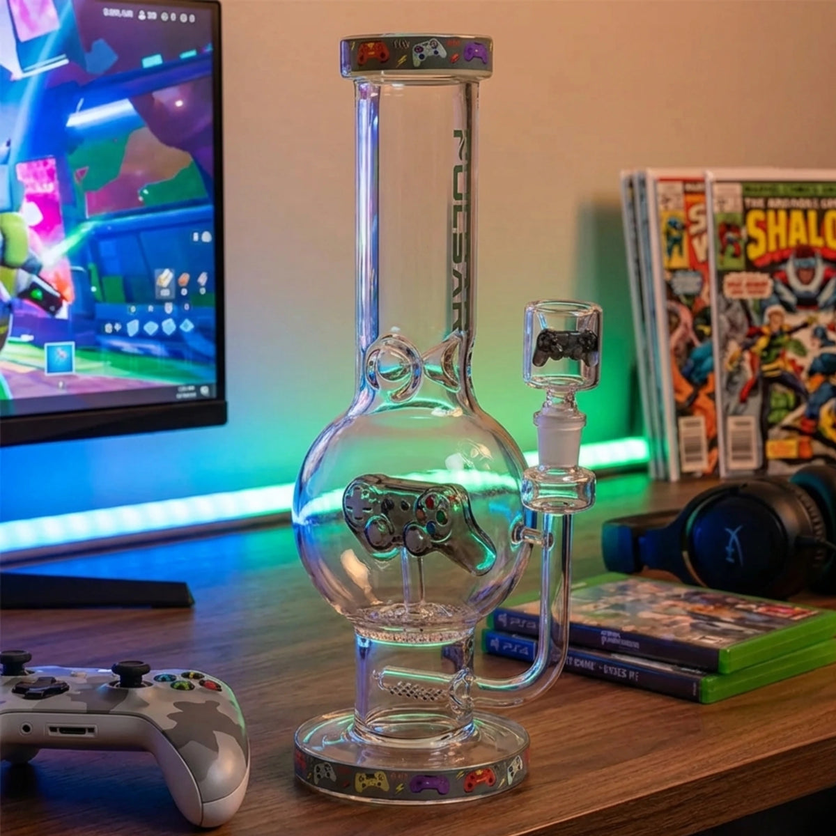 Glass Water pipe bong with gaming console design on a desk with a TV and gaming controllers in the background.