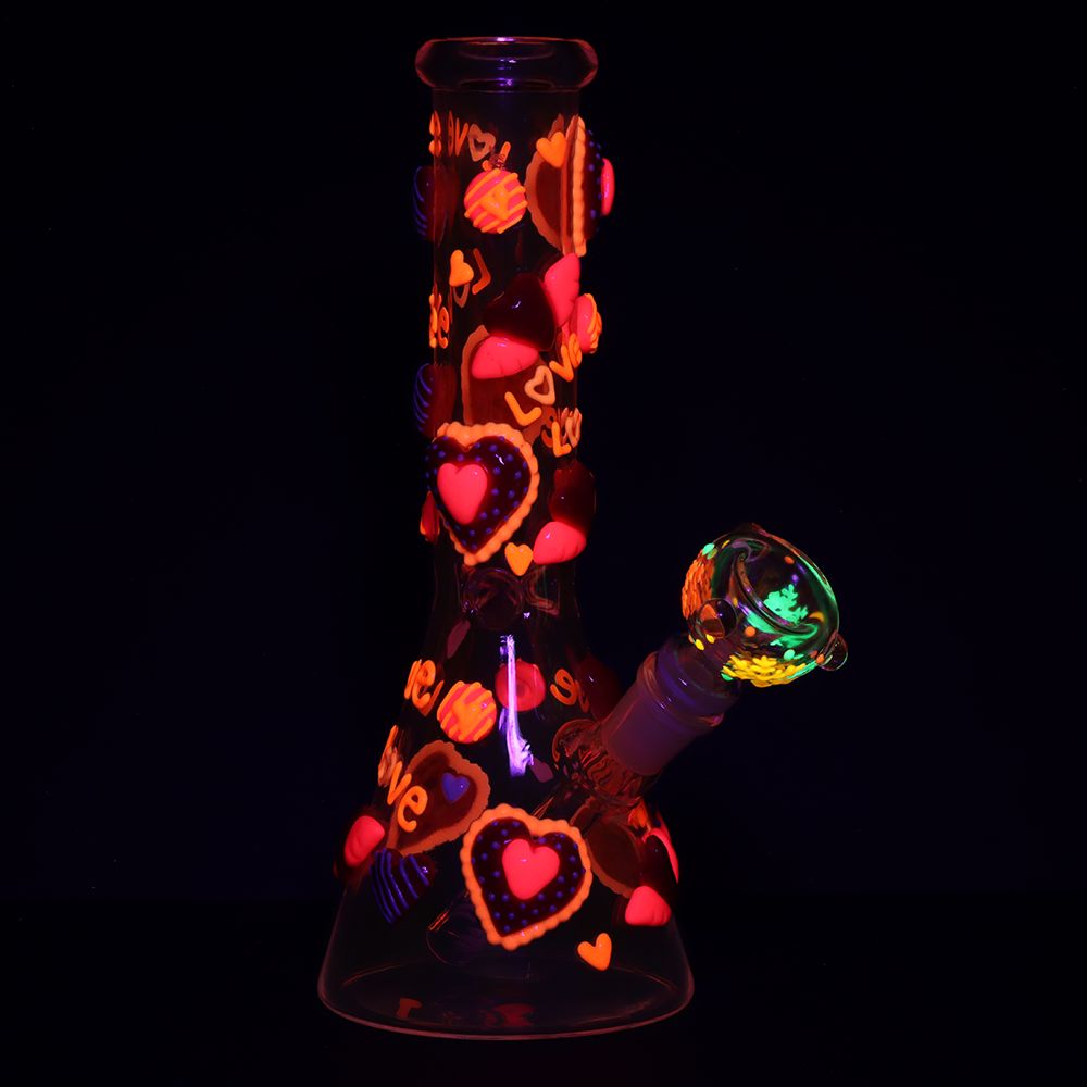 Glass glow in the dark water bong pipe with heart designs on a black background