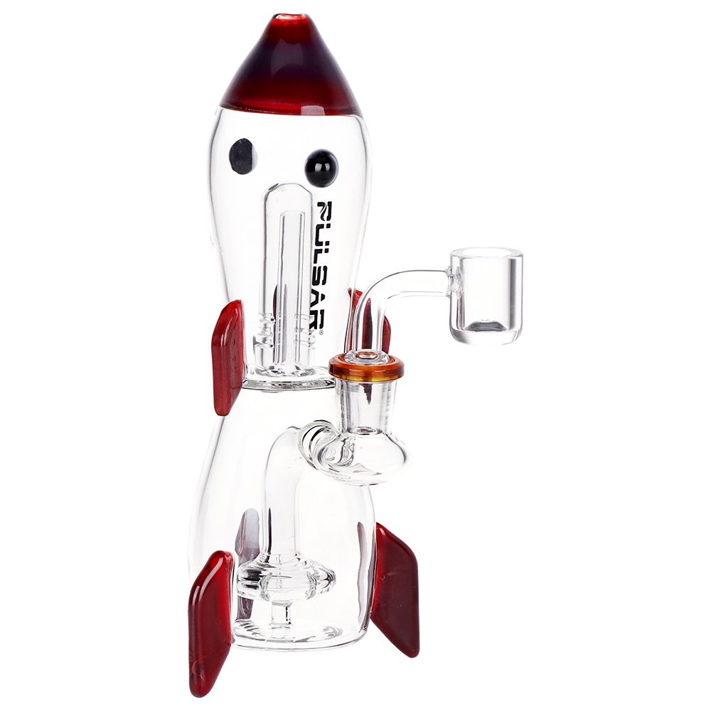 A novelty rocket-shaped glass Dab Rig water pipe with a clear body, red nose cone, red fins, black eyes, and a small clear bowl, shown on a plain white background.