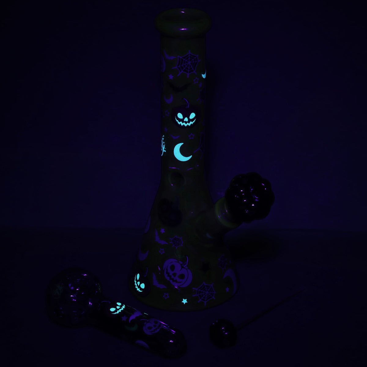 Glowing black glass pipe with Halloween-themed designs on a dark background